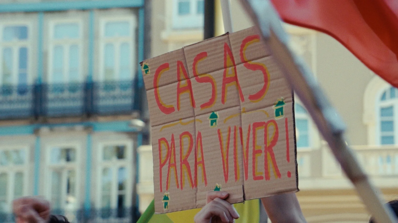 Cartel de cartón en una manifestación con el lema «Casas para vivir!» escrito en rojo sobre fondo marrón.