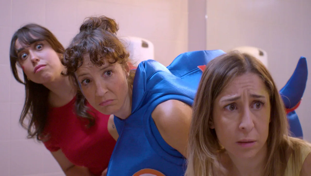 Fotograma de «Animadoras»: tres mujeres con disfraces de animación infantil miran a cámara, cansadas.
