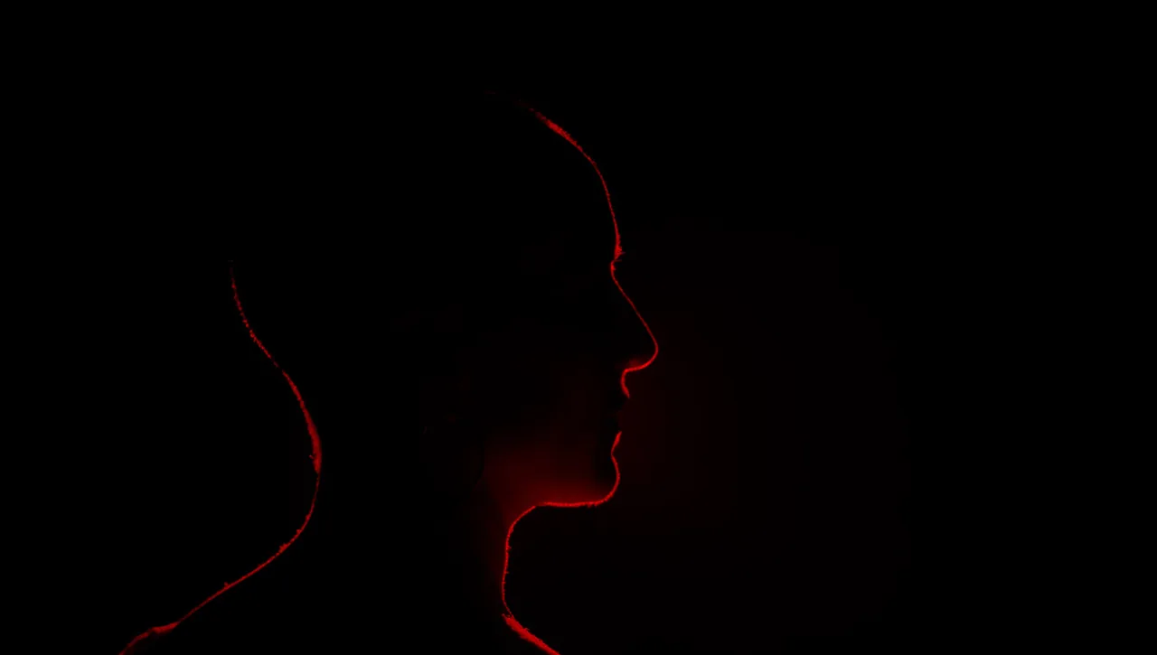 Fotograma de «Rincones»: el perfil de un rostro apenas iluminado por una luz roja, en la oscuridad.
