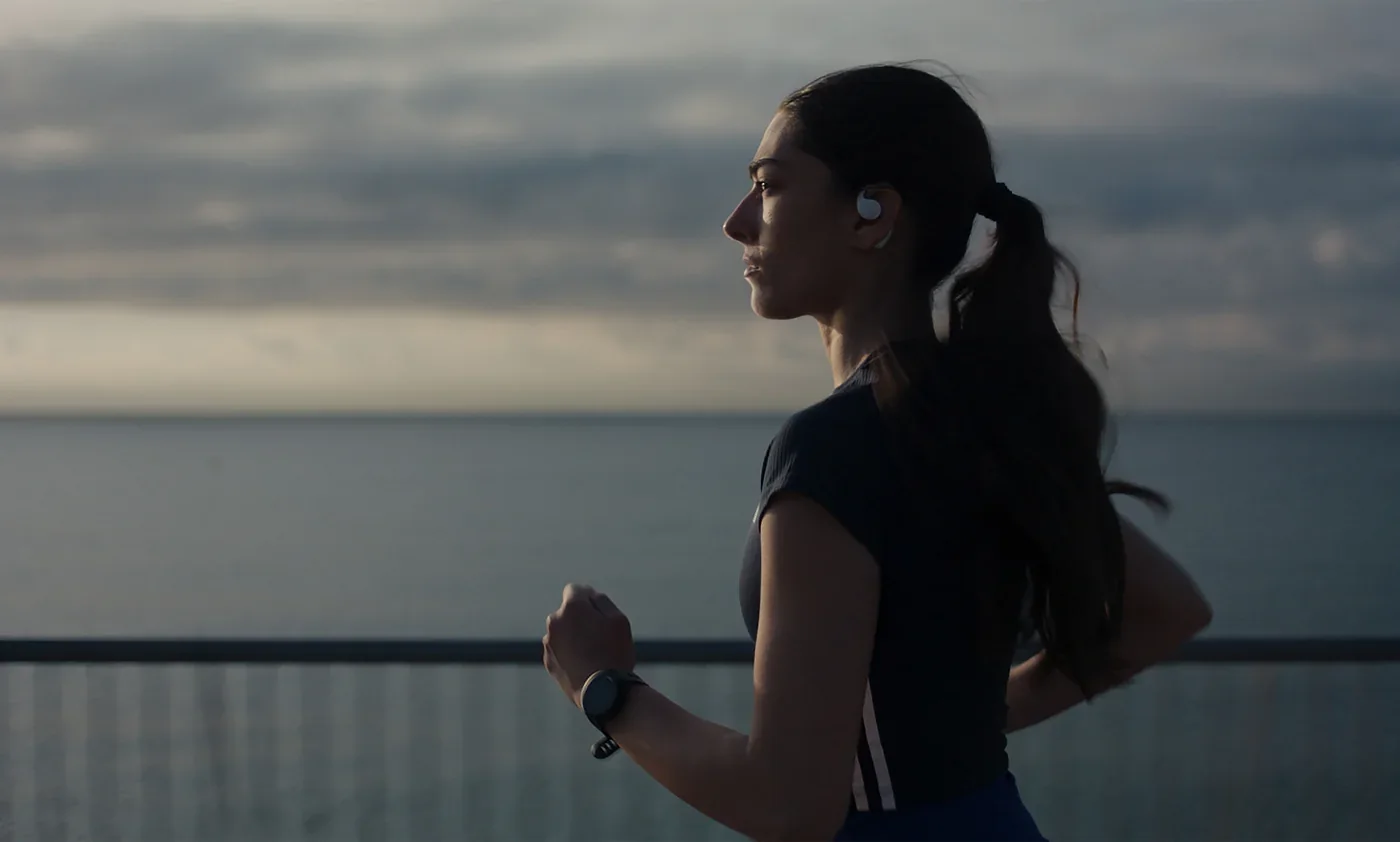 Fotograma de «Corredora»: una corredora con auriculares corre junto al mar al atardecer.