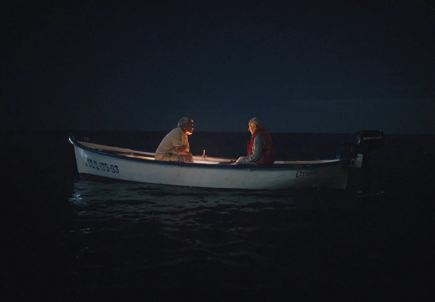 Fotograma de «Dos días»: dos hombres en una pequeña barca, de noche, en medio del mar.