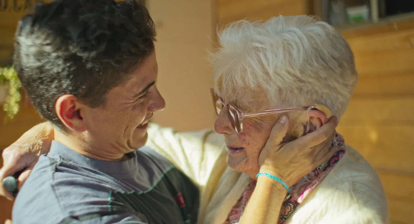 Fotograma de «Este cuerpo mío»: una persona joven abraza sonriendo a una mujer mayor.