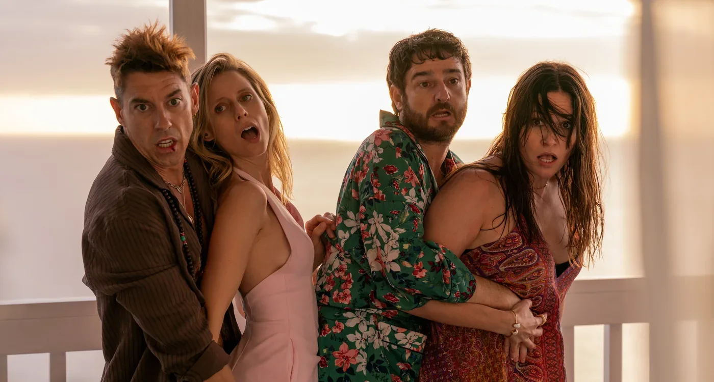 Fotograma de «Ni contigo ni sin mí»: dos parejas abrazadas y sorprendidas en una terraza junto al mar.